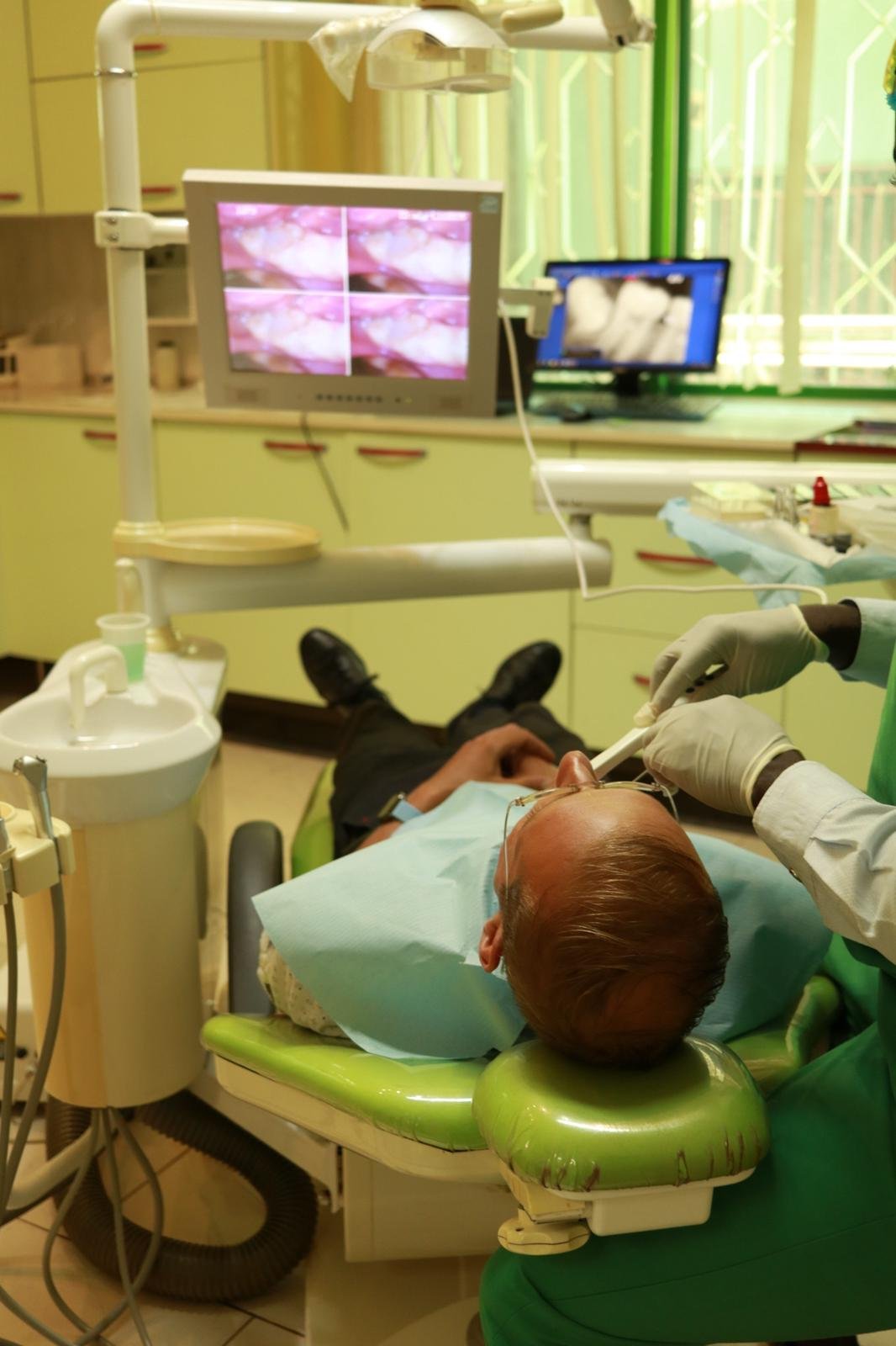 Patient being treated in the chair while a clinician works with an assistant at Lux Dental Clinic