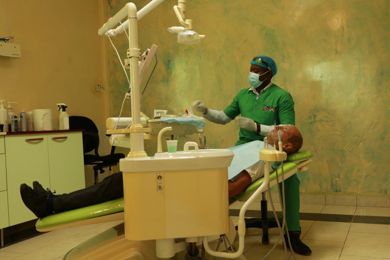 Clinician in scrubs, mask and gloves treating a patient at Lux Dental Clinic